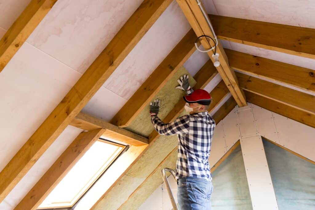 roofer installing roofing insulation, one of the main parts of a roof in order to your keep your heat or cool air from escaping