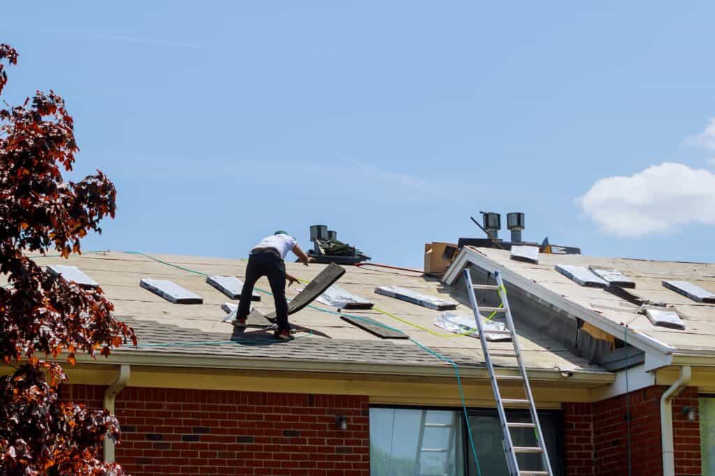 contractors performing a roof replacement on a residential home with shingles