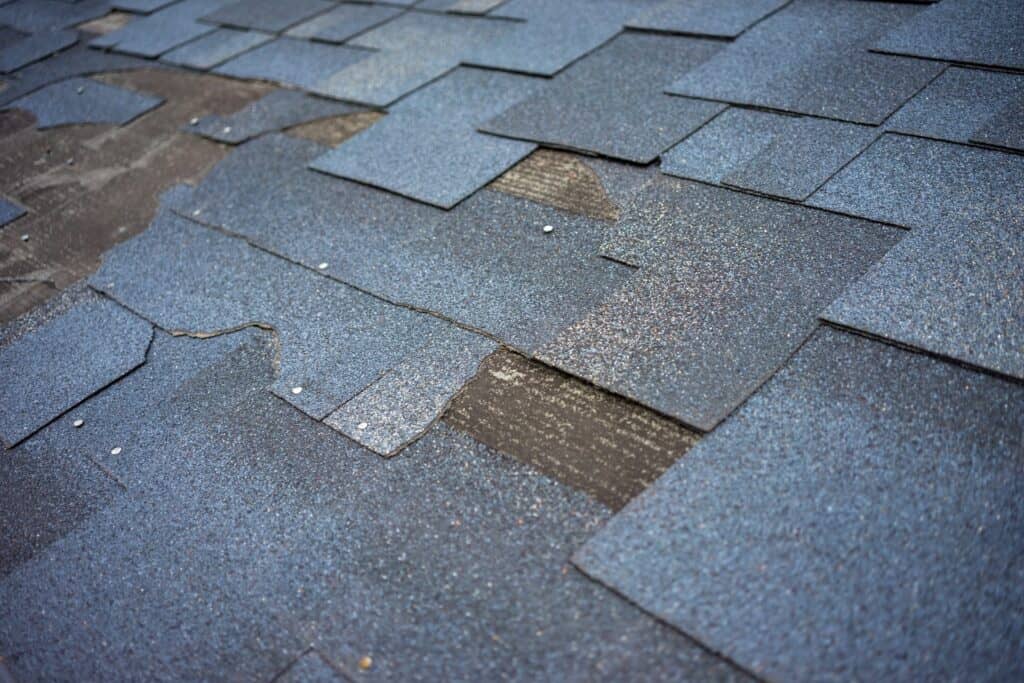 Сlose up view of bitumen shingles that are partially blown off