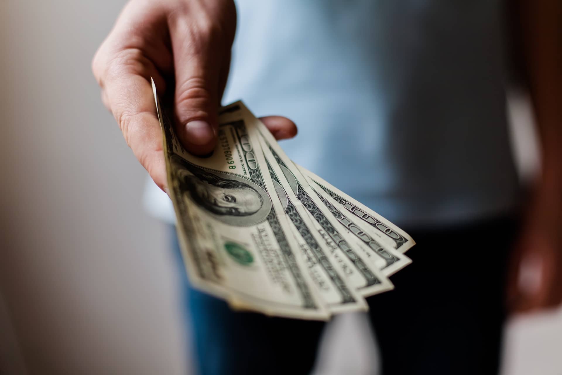 man holding cash - finance roof