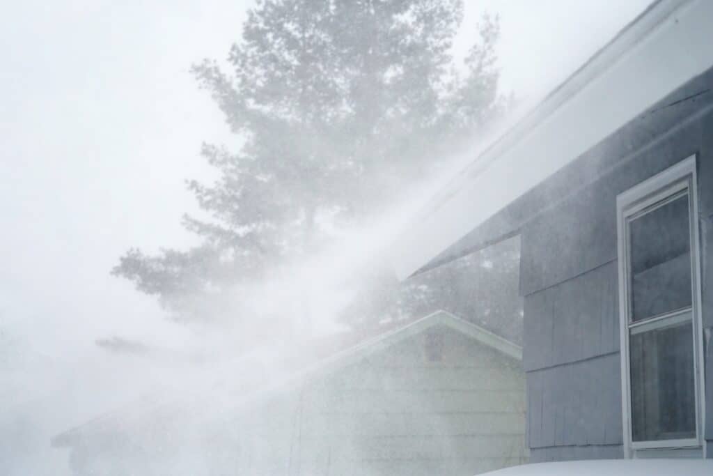 strong wind blowing snow off the roof in blizzard