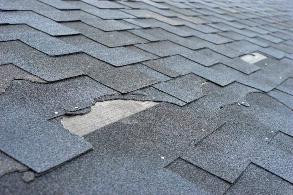 close up of broken shingles from hail damage on roof