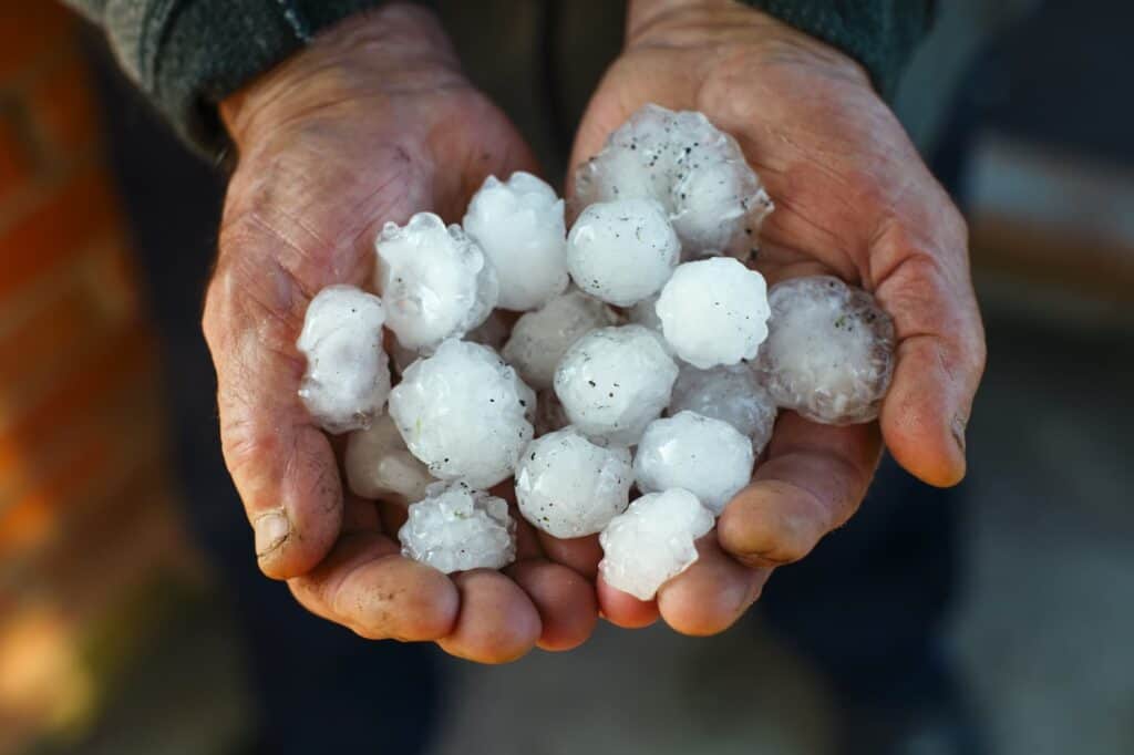 man holding hailstones to show the size