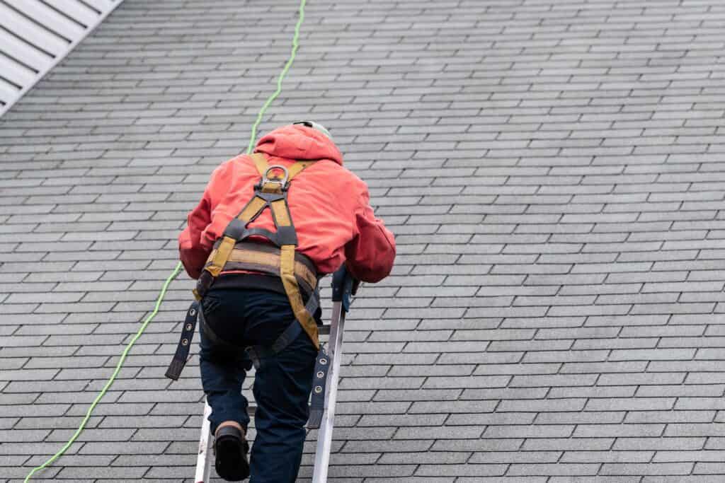 roof inspector on shingle roof looking for the source of a roof leak