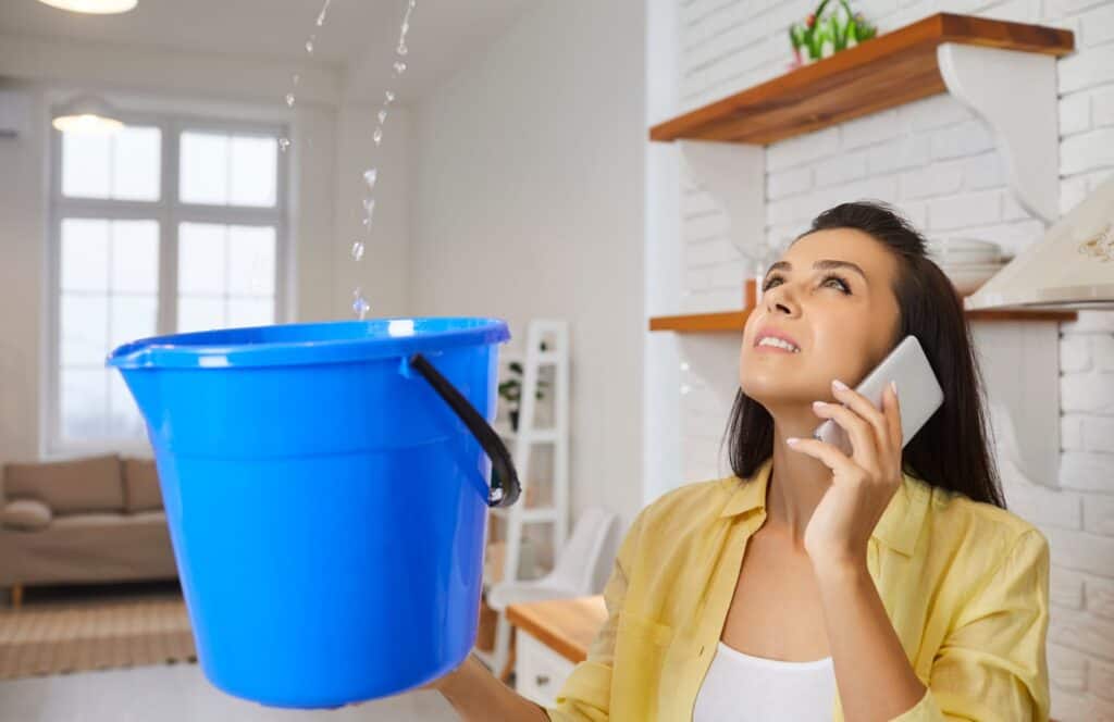 Woman holding a bucket to catch watcher from a roof leak